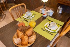 a table with a basket of bread and orange juice at Hôtel Le Cor de Chasse in Saint-Hubert