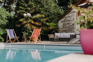 2 Stühle und eine Couch neben einem Pool in der Unterkunft Le moulin des Sens - SPA-SAUNA in Orthez