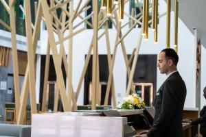 Ein Mann im Anzug, der an einem Schreibtisch steht. in der Unterkunft Al Khoory Courtyard Hotel in Dubai