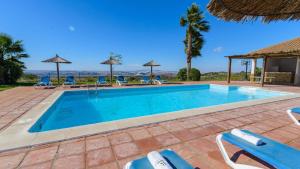 a swimming pool with blue chairs and umbrellas at Cortijo Escondido Arcos de la Frontera by Ruralidays in Arcos de la Frontera