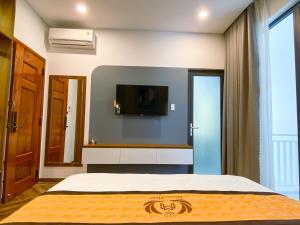 a bedroom with a bed and a tv on the wall at Khách sạn Miami Ninh Thuận in Phan Rang