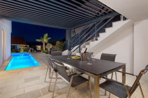une salle à manger avec une table et des chaises ainsi qu'une piscine dans l'établissement ChillZone - 20m to the sea, heated pool, à Trogir