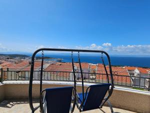 two chairs on a balcony with a view of the ocean at Apartments Adriatika in Makarska