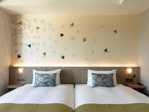 una camera con due letti e una parete con farfalle di Tokyu Stay Kanazawa a Kanazawa