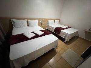 two beds in a small room with at Hotel Novo México in Guarulhos