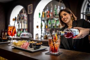 Una donna che versa un drink al bar di Rivalta Hotel - Alfieri Collezione a Firenze