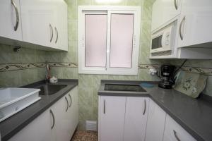 kuchnia z białymi szafkami, zlewem i kuchenką mikrofalową w obiekcie Apartamento Loli w mieście Nerja