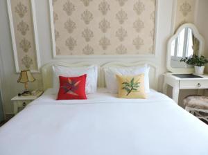 uma cama branca com três almofadas em CHEZ LOTUS VN em Ho Chi Minh