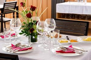 uma mesa branca com taças de vinho e um vaso de rosas em Vintage Lodge em Quatre Bornes