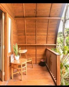 une terrasse couverte en bois avec une table et une chaise. dans l'établissement Umah lumbung bedugul, à Bedugul