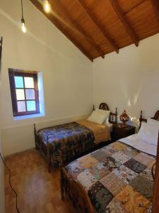 1 dormitorio con 2 camas y ventana en Finca Ancestros, en Tejeda