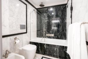 a bathroom with a white toilet and a black marble wall at Grand Hotel Parker's in Naples