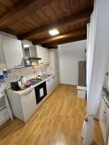 a kitchen with white cabinets and a wooden floor at Casa Vacanze Stezzano in Stezzano