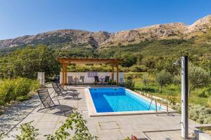 a swimming pool with chairs and a gazebo at Dvosobni apartman u kući s bazenom, 1 kat in Draga Bašćanska