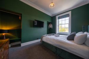 een slaapkamer met groene muren en een bed met een raam bij Luxurious GRAND 6 BR Home in BATH - Perfect for Groups & Sleeps 12! in Bath