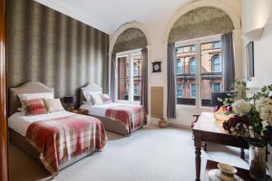 a bedroom with two beds and two windows at West George Street Apartment in Glasgow