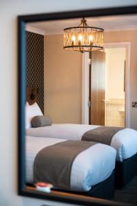 two beds in a hotel room with a mirror at Miller & Carter Sheffield by Innkeeper's Collection in Sheffield