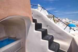 a staircase leading up to a building with a swimming pool at One of One - Aether in Oia