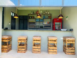 Outback Kenya Lodge في Machakos: بار به ثلاث كراسي وطاولة مع زجاجات النبيذ