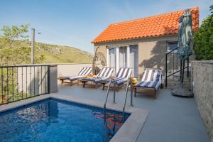 a swimming pool with two chairs and a house at Holiday Home Moliva in Donje Sitno