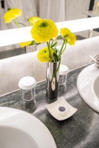 a vase with yellow flowers sitting on a bathroom counter at Grand Hotel Parker's in Naples