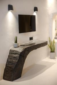 a rock table with a tv on a wall at One of One - Aurelia in Oia