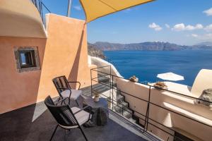 a balcony with chairs and a view of the ocean at One of One - Aurelia in Oia
