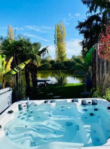 una vasca idromassaggio in un giardino con vista su uno stagno di Cottage, Lodge & Spa a Prouilly