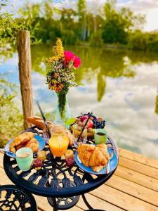 un tavolo con prodotti per la colazione e bevande su un tavolo vicino all'acqua di Cottage, Lodge & Spa a Prouilly