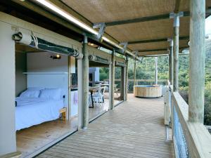 una terraza de madera con una cama y una mesa en AfriCamps Addo, en Swanepoelskraal