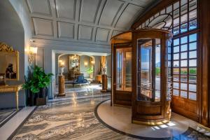 ナポリにあるグランド ホテル パーカーズの大きな窓とエレベーターのある華やかなロビー