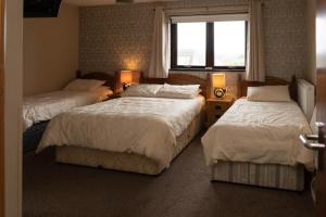 Habitación de hotel con 2 camas y ventana en Golf Links House en Newcastle
