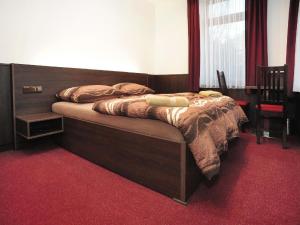 a bed in a bedroom with a red carpet at Penzion Budopartner in Jívka