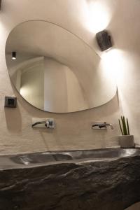 baño con espejo grande en la pared en One of One - Altheda en Oia