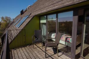 ein Haus mit einem Balkon mit einem Bett und Stühlen in der Unterkunft Lijo in Gargždai