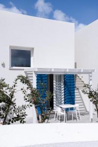 a white house with blue chairs and a table at EGIDA camere mediterranee in Favignana