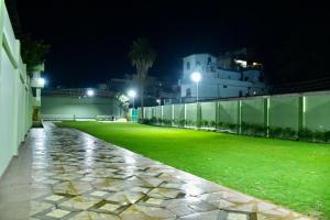 a green lawn at night with a fence and buildings at Maharani Garden in Haldwāni