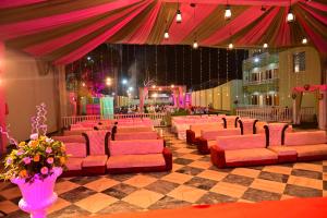 a large room with pink couches and a stage at Maharani Garden in Haldwāni