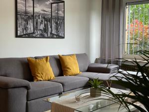 a living room with a gray couch and yellow pillows at Apart70-Modern Design I Garden with Terrace I Smart TV I Free Parking I Free WiFi in Hamm