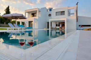 uma casa com dois copos de vinho ao lado de uma piscina em Sunlight Eros Villa em Áfra