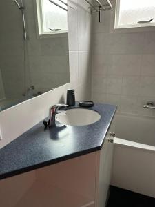 een badkamer met een wastafel, een spiegel en een bad bij Prins Heerlijk Amelander Kaap 81 in Hollum