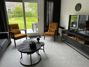 sala de estar con TV, mesa y sillas en Prins Heerlijk Amelander Kaap 81, en Hollum