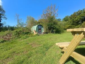 a green tent in a field with a bench at MotoCamp Wales in Dolgellau