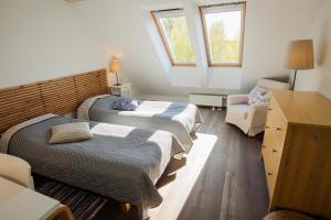 - une chambre avec deux lits, une chaise et deux fenêtres dans l'établissement Lijo, à Gargždai