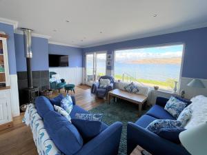 a living room with blue furniture and a large window at Craignethan in Kames
