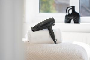 a black hair dryer sitting on top of a chair at Stylish House - Close to City Centre and Luton Airport - Free Parking, Super-Fast Wifi, Garden and Smart TV with Netflix by Yoko Property in Luton