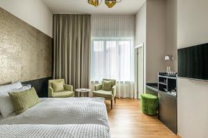 ルツェルンにあるBoutique Hotel KARLのベッド1台と椅子2脚が備わるホテルルームです。