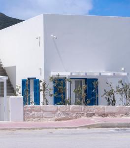 a white building with blue shutters on a street at EGIDA camere mediterranee in Favignana