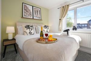 a bedroom with a bed with a bottle of wine and fruit at Stylish House - Close to City Centre and Luton Airport - Free Parking, Super-Fast Wifi, Garden and Smart TV with Netflix by Yoko Property in Luton