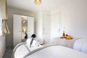 a white bedroom with two beds and a mirror at Stylish House - Close to City Centre and Luton Airport - Free Parking, Super-Fast Wifi, Garden and Smart TV with Netflix by Yoko Property in Luton